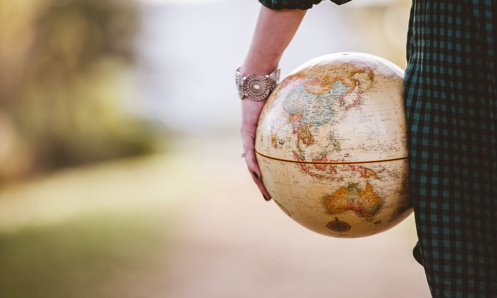 Eine junge Welt hält einen Spielball an der Seite, auf dem die Weltkarte abgebildet ist.