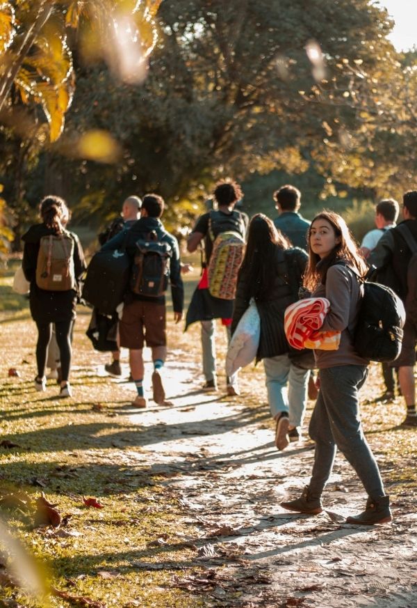 eine Gruppe Menschen wandert in einem herbstlichen Wald. Eine junge Frau im Vordergrund dreht sich zum Betrachter um.