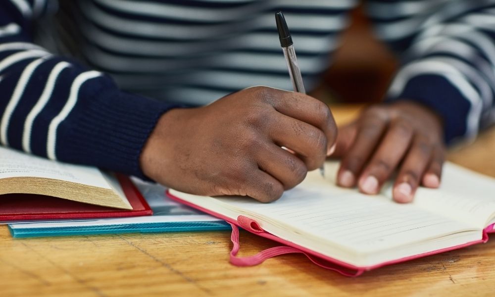 Ein junger Mann macht sich Notizen in einem Buch.