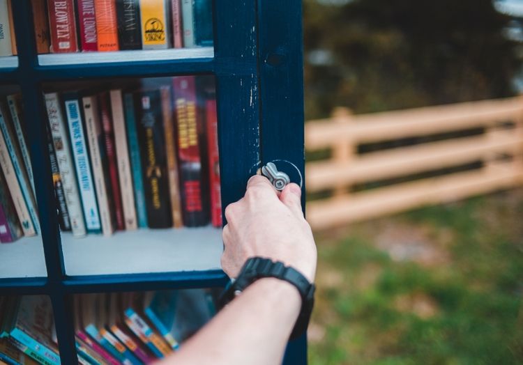 Eine Person öffnet gerade einen Bücherschrank im freien, der dazu da ist, Bücher zu tauschen.
